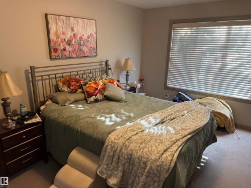 Room featuring a window with horizontal blinds, neutral wall paint, and a metal headboard - 7065 Cardinal Way Sw, Edmonton, AB - Indoor Photo Showing Bedroom