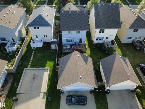 Expansive backyard with a manicured lawn, concrete patio, and a storage shed - 7065 Cardinal Way Sw, Edmonton, AB - Outdoor