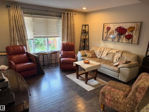 Recessed ceiling lighting, a large window with blinds, and dark wood-finish flooring - 7065 Cardinal Way Sw, Edmonton, AB - Indoor Photo Showing Living Room