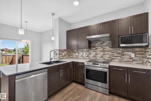 Kitchen with wood-finish flooring, dark wood cabinetry, white countertops, and a tiled backsplash - 1404 25 Avenue Nw, Edmonton, AB - Indoor Photo Showing Kitchen With Double Sink With Upgraded Kitchen