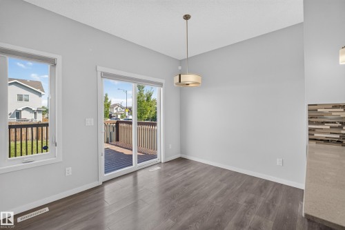 Sliding glass door leading to a wooden deck, wood-finish flooring, contemporary pendant light fixture, and a tiled backsplash feature - 1404 25 Avenue Nw, Edmonton, AB - Indoor Photo Showing Other Room