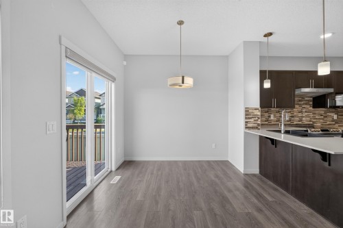 Wood-finish flooring throughout, with a contemporary drum pendant light fixture - 1404 25 Avenue Nw, Edmonton, AB - Indoor Photo Showing Kitchen With Upgraded Kitchen