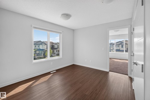 Wood-finish flooring with white baseboards, large double window, and recessed ceiling lighting - 1404 25 Avenue Nw, Edmonton, AB - Indoor Photo Showing Other Room