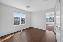 Wood-finish flooring with white baseboards, large double window, and recessed ceiling lighting - 