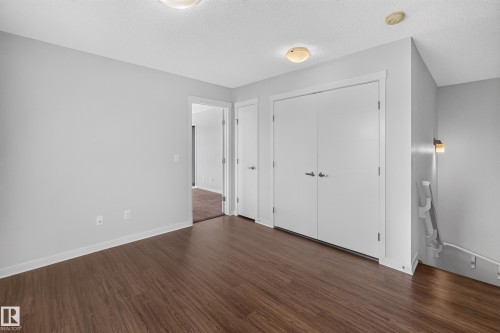 Wood-finish flooring, light gray wall paint, white trim, and a white bi-fold closet door - 1404 25 Avenue Nw, Edmonton, AB - Indoor Photo Showing Other Room