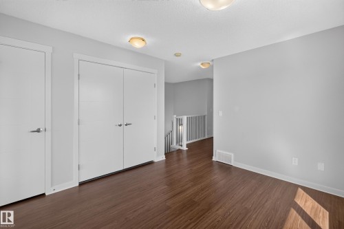 Wood-finish flooring, white trim details, flush mount lighting, and neutral wall paint - 1404 25 Avenue Nw, Edmonton, AB - Indoor Photo Showing Other Room