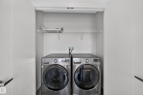 Integrated laundry appliances within a dedicated closet, featuring a wire storage shelf and white paneled bifold doors - 1404 25 Avenue Nw, Edmonton, AB - Indoor Photo Showing Laundry Room