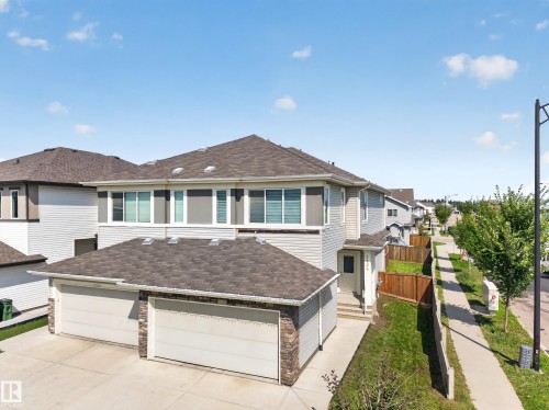 Contemporary exterior with two garage doors, stone accents, and a paved driveway - 1404 25 Avenue Nw, Edmonton, AB - Outdoor