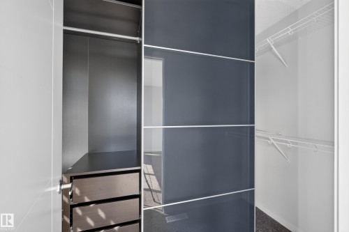 Built-in closet system featuring a hanging rod, integrated drawers, sliding panel doors, and wire shelving - 1404 25 Avenue Nw, Edmonton, AB - Indoor