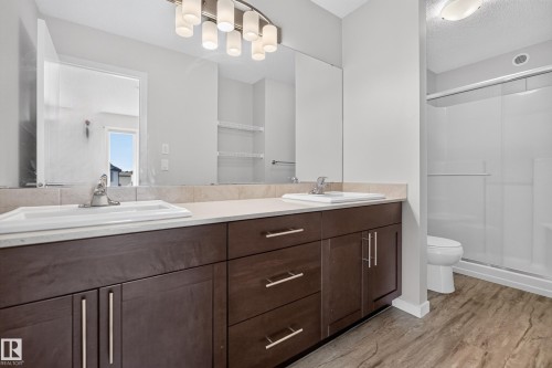 Double vanity with undermount sinks, wood-finish cabinetry, and brushed nickel hardware - 1404 25 Avenue Nw, Edmonton, AB - Indoor Photo Showing Bathroom