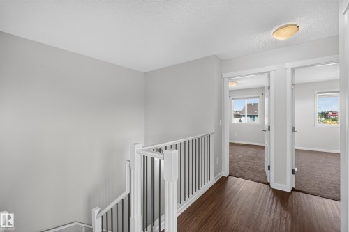 Light gray painted walls, wood-finish flooring, white spindle railing, and overhead lighting fixtures - 1404 25 Avenue Nw, Edmonton, AB - Indoor Photo Showing Other Room