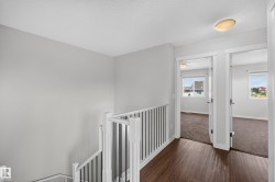 Light gray painted walls, wood-finish flooring, white spindle railing, and overhead lighting fixtures - 