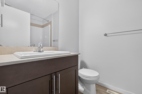 Dark wood-finish vanity with chrome hardware, an integrated rectangular sink, and a light-toned countertop - 1404 25 Avenue Nw, Edmonton, AB - Indoor Photo Showing Bathroom