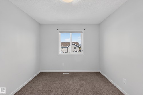 Neutral wall paint, brown carpeting, and a single window with white trim - 1404 25 Avenue Nw, Edmonton, AB - Indoor Photo Showing Other Room
