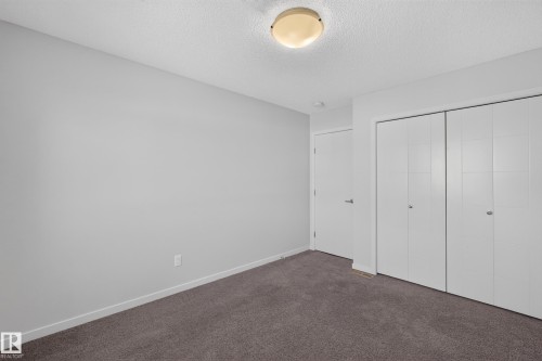 Plush carpeting, light-toned wall paint, ceiling-mounted lighting fixture, and white bi-fold closet doors - 1404 25 Avenue Nw, Edmonton, AB - Indoor Photo Showing Other Room