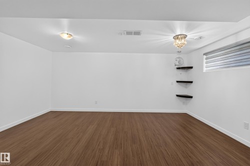 Wood-finish flooring, white walls, flush mount lighting, decorative chandelier, and window with blinds - 1404 25 Avenue Nw, Edmonton, AB - Indoor Photo Showing Other Room