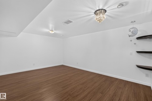 Wood-finish flooring, white walls, recessed lighting, and a crystal chandelier - 1404 25 Avenue Nw, Edmonton, AB - Indoor Photo Showing Other Room