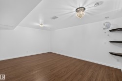 Wood-finish flooring, white walls, recessed lighting, and a crystal chandelier - 