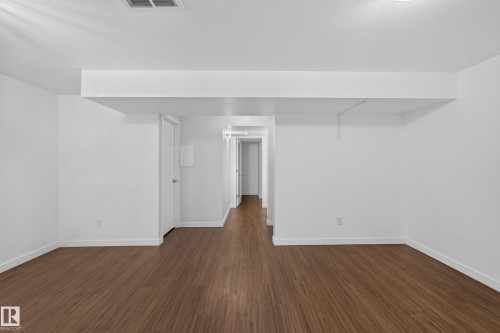 Wood-finish flooring throughout, white walls, recessed ceiling light, and a white interior door with hardware - 1404 25 Avenue Nw, Edmonton, AB - Indoor