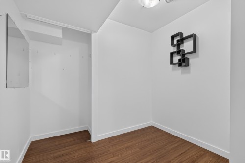 Wood-finish flooring with white baseboards, a ceiling-mounted light fixture, and a built-in alcove - 1404 25 Avenue Nw, Edmonton, AB - Indoor Photo Showing Other Room