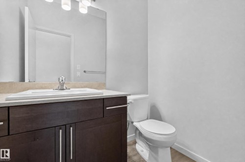 Dark wood-finish vanity with silver-tone hardware, rectangular undermount sink, and light countertop - 1404 25 Avenue Nw, Edmonton, AB - Indoor Photo Showing Bathroom