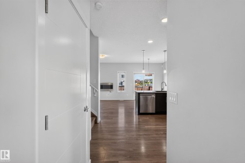 Wood-finish flooring, recessed lighting, white interior walls, and a kitchen island with pendant lighting and stainless steel appliances - 1404 25 Avenue Nw, Edmonton, AB - Indoor Photo Showing Other Room
