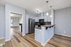 Well-appointed kitchen featuring light-colored cabinetry, stainless steel refrigerator, dark countertops, and a full backsplash - 