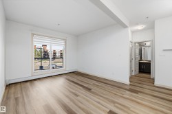 Wood-finish flooring, white walls, and a large window with blinds - 
