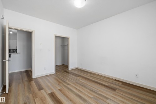 Wood-finish flooring, white painted walls, and a ceiling-mounted light fixture - #207 304 Amblside Li Sw Sw, Edmonton, AB - Indoor Photo Showing Other Room