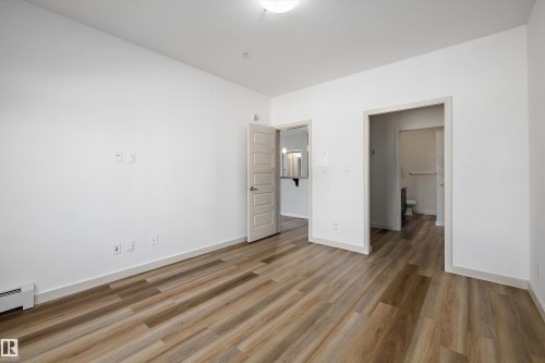 Wood-finish flooring, white walls, and a ceiling-mounted light fixture - #207 304 Amblside Li Sw Sw, Edmonton, AB - Indoor Photo Showing Other Room