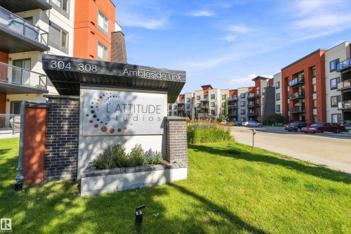 Building exterior with brick and paneling accents, featuring balconies with glass railings - #207 304 Amblside Li Sw Sw, Edmonton, AB - Outdoor