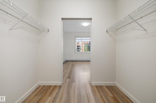 Walk-through closet with wire shelving and wood-finish flooring - #207 304 Amblside Li Sw Sw, Edmonton, AB - Indoor With Storage