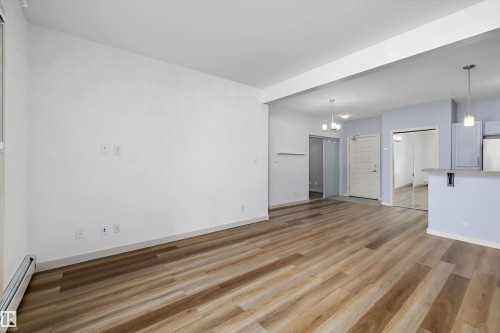 Wood-finish flooring throughout, white walls, and a recessed ceiling beam - #207 304 Amblside Li Sw Sw, Edmonton, AB - Indoor
