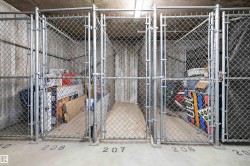 Chain-link storage cages with concrete walls and numbered floor markings - 