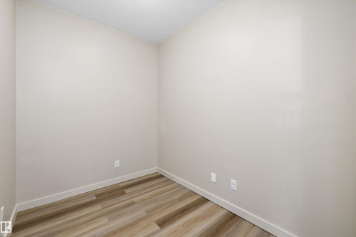 Neutral-toned walls, wood-finish flooring, and white trim - #207 304 Amblside Li Sw Sw, Edmonton, AB - Indoor Photo Showing Other Room