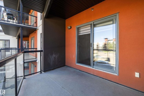 Private balcony with concrete flooring, glass and metal railings, and a sliding glass door - #207 304 Amblside Li Sw Sw, Edmonton, AB - Outdoor With Exterior