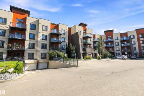 Modern multi-story building featuring balconies with glass railings, an integrated underground parking garage, and structured landscaping - #207 304 Amblside Li Sw Sw, Edmonton, AB - Outdoor With Facade