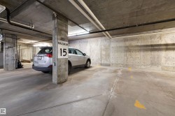Concrete subterranean parking space with exposed concrete walls, structural columns, and overhead utility piping - 
