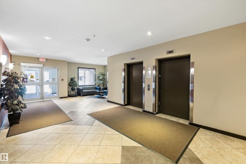 Tiled flooring entrance area featuring two elevators with stainless steel accents and recessed lighting - #207 304 Amblside Li Sw Sw, Edmonton, AB - Indoor Photo Showing Other Room