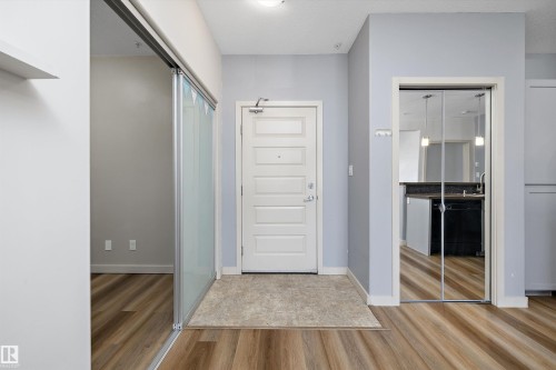 Wood-finish flooring with a neutral entrance mat - #207 304 Amblside Li Sw Sw, Edmonton, AB - Indoor Photo Showing Other Room