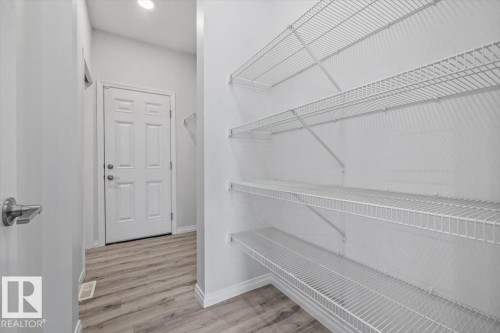 Wire shelving storage system, paneled door, wood-finish flooring, recessed lighting - 1014 Daniels Loop Sw, Edmonton, AB - Indoor With Storage