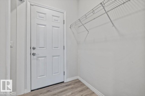 White six-panel interior door with polished chrome hardware, light wood-finish flooring, and white wire shelving - 1014 Daniels Loop Sw, Edmonton, AB - Indoor