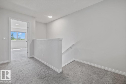 Carpeted landing with white balustrade and handrail, recessed lighting, and white trim - 1014 Daniels Loop Sw, Edmonton, AB - Indoor Photo Showing Other Room