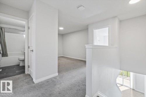 Plush carpeted flooring, recessed lighting, white interior doors, and a bathroom with a white tub and subway-tiled shower surround - 1014 Daniels Loop Sw, Edmonton, AB - Indoor