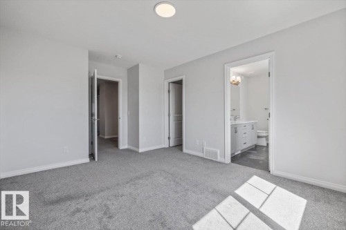 Spacious room featuring gray carpeting and white walls - 1014 Daniels Loop Sw, Edmonton, AB - Indoor
