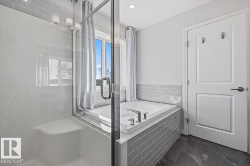 Glass-enclosed shower with integrated seating, a built-in soaking tub, subway tile surround, dark-toned floor tiles, and a window with natural light - 1014 Daniels Loop Sw, Edmonton, AB - Indoor Photo Showing Bathroom