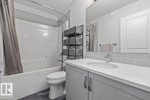 Light gray subway tile backsplash, white countertop with integrated sink, chrome faucet, and gray vanity cabinetry - 1014 Daniels Loop Sw, Edmonton, AB - Indoor Photo Showing Bathroom
