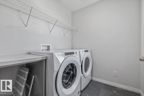 Laundry area featuring dark-toned floor tiling, light gray wall paint, and a built-in countertop - 1014 Daniels Loop Sw, Edmonton, AB - Indoor Photo Showing Laundry Room