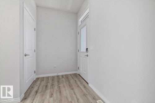 Wood-finish flooring with white baseboards, a white interior door, and an exterior door with frosted glass - 1014 Daniels Loop Sw, Edmonton, AB - Indoor Photo Showing Other Room
