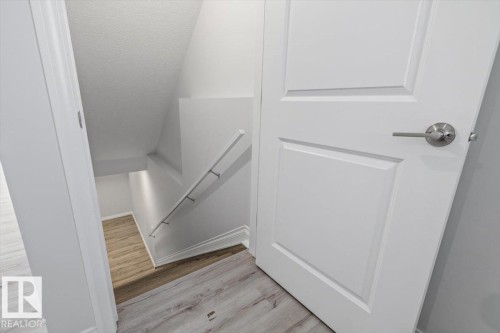 White interior door with brushed nickel hardware, wood-finish flooring, and white painted walls - 1014 Daniels Loop Sw, Edmonton, AB - Indoor Photo Showing Other Room